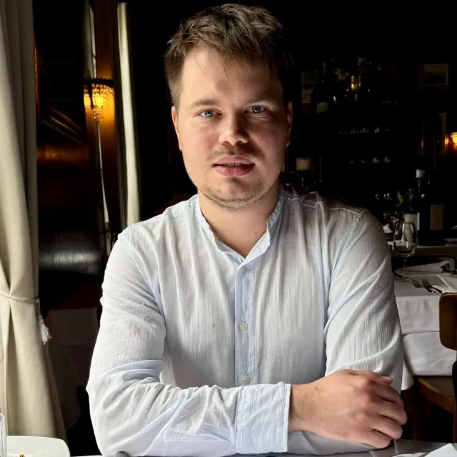 Daniil Emtsev, seated at a table in a white shirt
